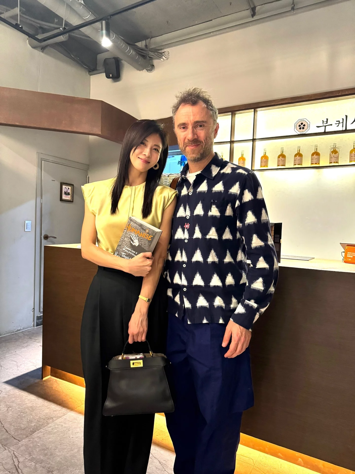 背心不一定只能走休閒路線，選對有結構感的寬肩背心，再搭配高腰西裝褲，就能在露膚與俐落之間找到平衡，既保有優雅大器，也能穿出清爽年輕感。河智苑以明黃色寬肩背心搭配黑色高腰西裝褲現身，搭配Fendi Peekaboo手袋，整體配色簡潔，卻很有記憶點。背心透過微寬肩線條撐起上半身輪廓，不只修飾手臂與肩頸比例，也讓整體看起來更挺拔有精神。亮眼的黃色調則成功提亮膚色，讓造型在優雅之中多了一點活力。