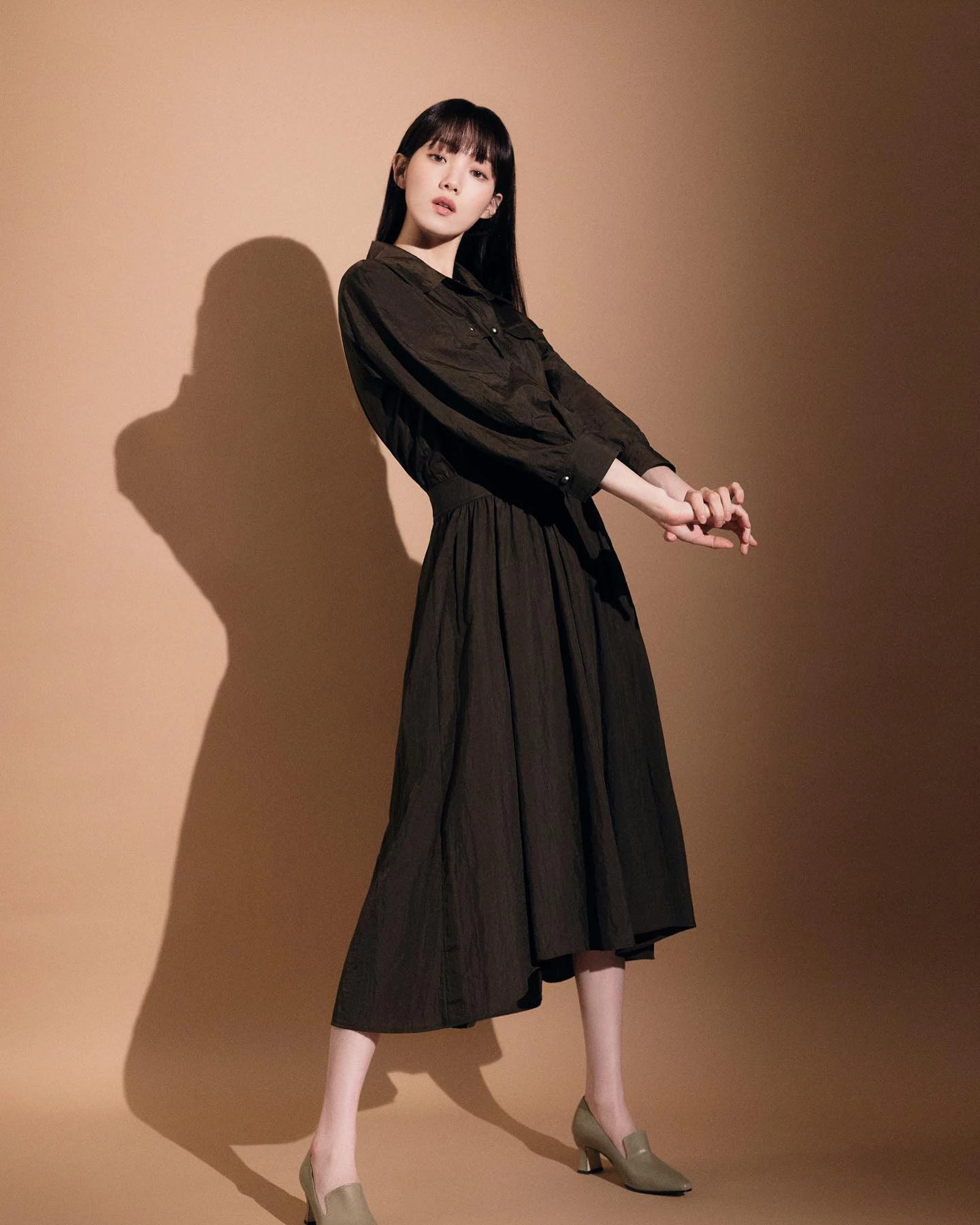 李聖經這套私服選擇一件深棕色長袖洋裝作為主角,本身就具備視覺收縮效果,再加上高腰收束設計,自然把腰線往上提,比例立刻被拉長。這件洋裝最大亮點在於A字剪裁,從腰部向下展開,是公認的「藏肉神器」,對於大腿與臀部修飾特別有感,視覺至少少5公斤。