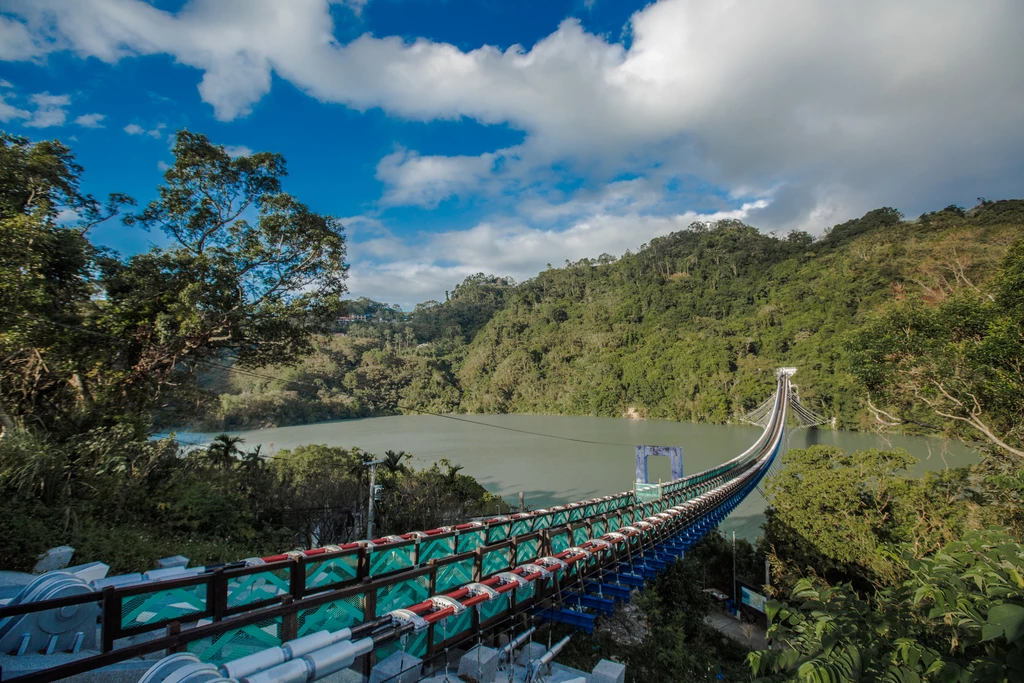 作為全台最長的懸索橋,桃園復興區人氣景點「新溪口吊橋」歷經多時修繕後,正式對外開放,並祭出限時免門票入園優惠(至 6 月 30 日止)。新溪口吊橋是一座相當細長且優美的吊橋,全長 303 公尺,吊橋中央可觀賞美麗的大漢溪河谷風貌、群山環繞景致,以及石門水庫豐沛的蓄水景觀。橋身完美融入象徵守護意涵的泰雅族祖靈之眼圖騰,宛如山谷間優美的微笑曲線。