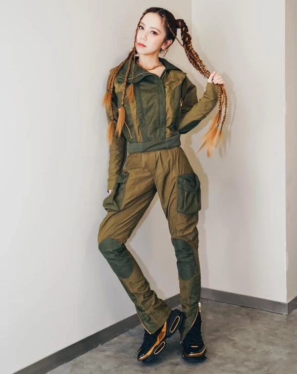 這一身略帶軍裝感的綠色拼接工裝，便是她在舞台與現實間切換的「硬核浪漫」。這套造型，徹底玩轉了機能美學，透過異材質拼接與俐壯的短版剪裁，將軍裝從傳統的粗獷中解放，注入了一種專屬於街頭的銳利精緻感。