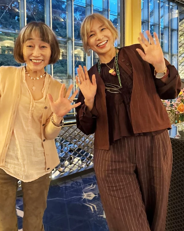 山口智子這次現身，則是運用了不同深淺的巧克力色，外罩一件帶有細膩直條紋的短版外套，內搭層次豐富的黑色蕾絲與荷葉邊上衣。這種「外剛、內柔」的層次搭配法，讓深色系視覺不再扁平，反而透出一種法式的復古優雅。下半身搭配與外套同系列的條紋寬褲，更是點睛之筆，讓整體比例顯得纖細且修長。最吸睛的莫過於，她在這樣沉穩的底色上，適時加入「亮點配件」的點綴作法，也瞬間打破了深色服飾的嚴肅感，展現出她獨有的俏皮與活潑。