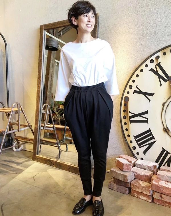 鈴木保奈美僅用最經典的黑白配,就穿出強烈的時髦感。她選擇一件帶有立體剪裁、一字領的七分袖白上衣,下半身搭配高腰且大腿廓形寬鬆、小腿收緊的黑色飛鼠褲。一般人穿黑白配最怕流於呆板的上班族制服,秘訣就在於「打破常規的剪裁」。