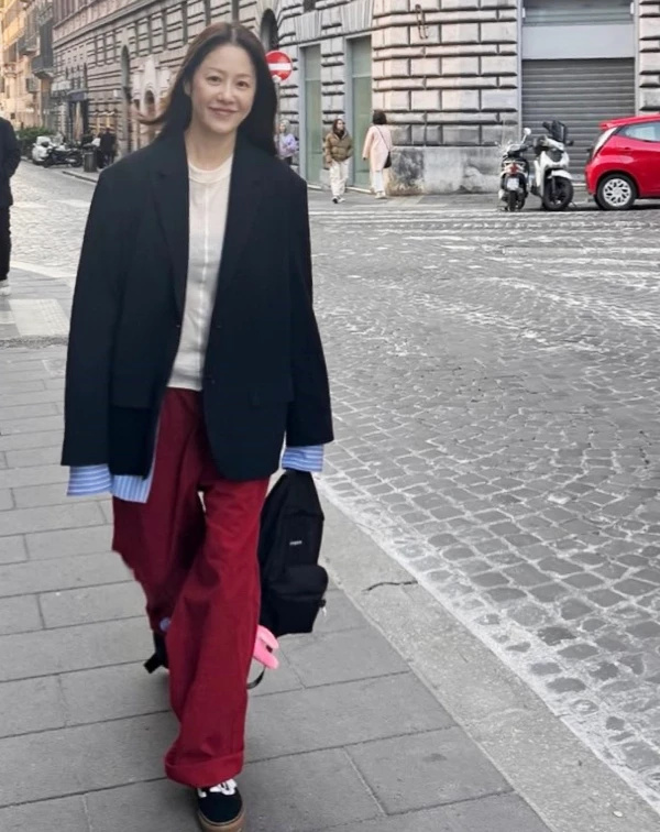 高賢廷在歐洲街頭漫步的街頭穿搭,大膽選用沉穩的黑色西裝外套,搭配米白色上衣與清涼感十足的藍條紋襯衫,最精彩的莫過於刻意露出的襯衫袖口與下襬,靠著這種「長、短不一」的層次細節,瞬間化解了西裝外套的正式感,增添視覺律動。下半身,則大膽搭配一條高飽和度的紅色寬褲,這抹重色豔彩,不僅點亮了街頭氛圍,更與黑色外套混搭出一種對比的活力。 對於想學習的同齡大眾來說,我們只要敢於在黑、白、灰的基本單品中,加入一抹鮮明色彩,就能瞬間打破僵硬線條,在專業感中保留住如藝術家般的年輕氣場。