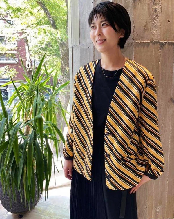 松隆子這次則改用全黑內搭當基底,原本比較容易顯得沉悶,但外面多罩了一件黃、黑斜條紋短版外套後,整個人立刻有精神很多。尤其,斜條紋本來就比橫條紋更有延伸感,看起來也會比較修飾身形,再上短版和七分袖的設計,視覺上也讓比例變得更輕盈。配件部分,她也沒有搭太多,只用一條簡單的金屬短鍊點綴,反而讓整體看起來乾淨又有重點。這樣的穿法,其實很適合平常喜歡黑色系的人,不會太單調,又能保留一點俐落感。