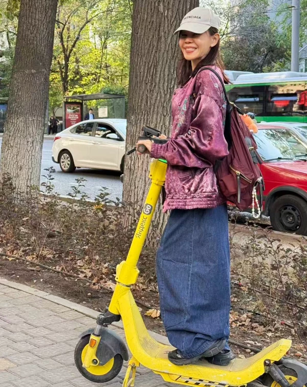 這張騎著共享滑板車的照片,完美展現了彭佳慧不費力的私服功力。暗紫色刺繡緞面夾克,自帶Old School味,另外搭配一條極寬的深藍色牛仔長裙、棒球帽與後背包,舒適自在,時髦得像個潮流Icon。