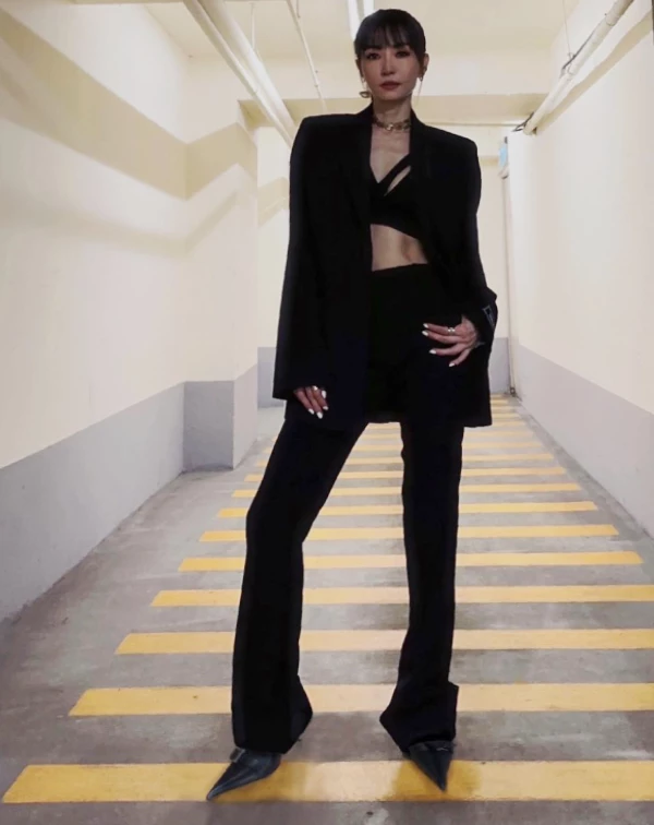 如此極致的「俐落黑」美學，完全就是霸氣女總的既視感來著！極簡的黑色西裝，搭配剪裁別緻的短版內搭，她精準地運用了「寬鬆廓形」與「短版上衣」的強烈對比，不僅襯托出腰部的緊緻線條，更讓整體氣場顯得冷冽又高級。這種「上短下長」的穿搭邏輯，也能巧妙地拉長了下半身比例，即便身穿全身黑，依舊能透過衣料剪裁穿出層次感。