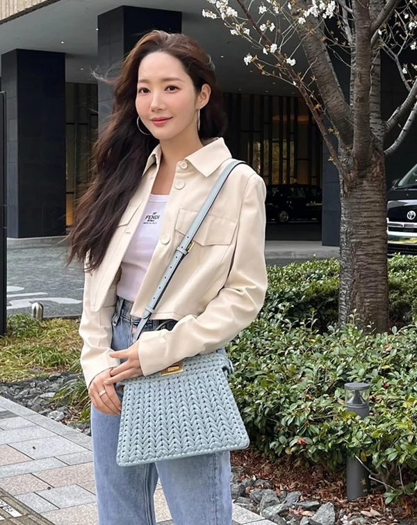 當女性邁入40歲,身上的包款往往流於過度嚴肅或一成不變的經典皮質。朴敏英在這套日常街拍中,雖然穿著剪裁挺拔、帶著幹練墊肩的米色短夾克與高腰直筒牛仔褲,但她聰明地挑選了一款水藍色針織編織紋理的Fendi「Peekaboo」包。