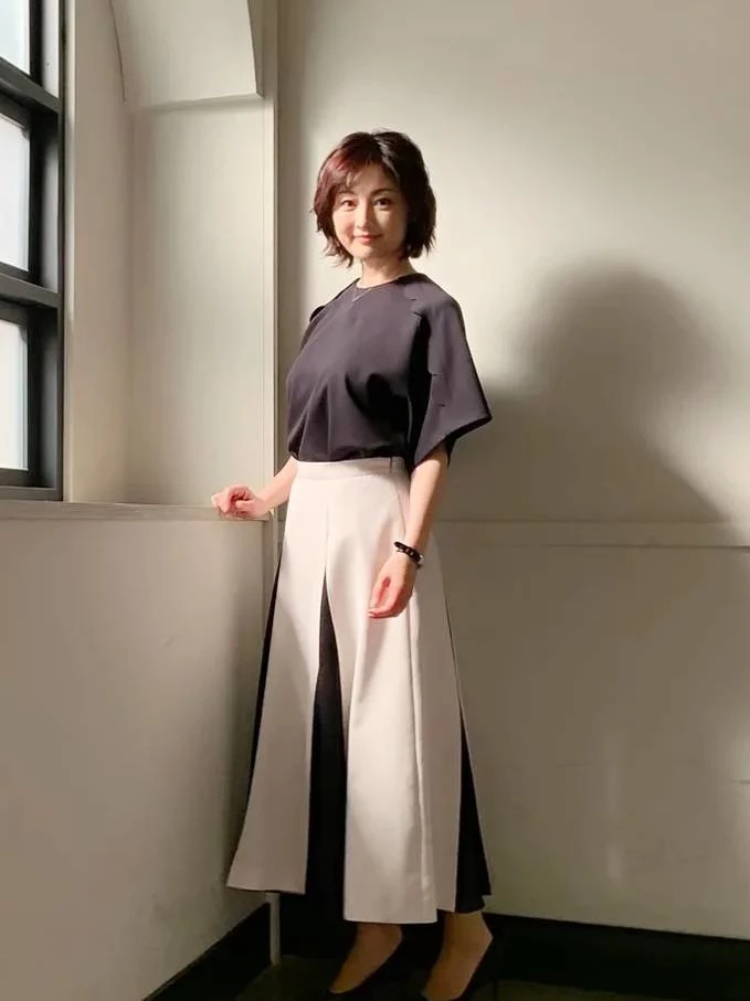 常盤貴子將「簡約而不簡單」的真諦發揮得淋漓盡致。她選擇了一件沉穩的深色五分袖圓領上衣，圓潤的微飛鼠袖剪裁，能巧妙修飾手臂與肩膀線條。最厲害的，莫過於下半身那條高腰雙色拼接裙，正面看是優雅的米白色Ａ字線條，但隨著開衩的剪裁設計，內襯的深色布料若隱若現，更拉長了下半身的視覺比例，美得非常內斂。