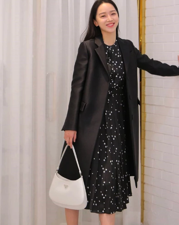 申惠善簡直是「人間Prada」的親善大使吧!手中那只白色的「Cleo」包款,憑藉其標誌性的弧形結構與拋光皮革的細膩光澤,在沉穩的全黑穿搭中,躍然而出,成為視覺的核心。「Cleo」包款那種融合了90年代復古極簡線條,與申惠善清冷而精緻的氣質完美契合,即便只是靜靜站立,也散發出一種高級且不費力的時尚感。