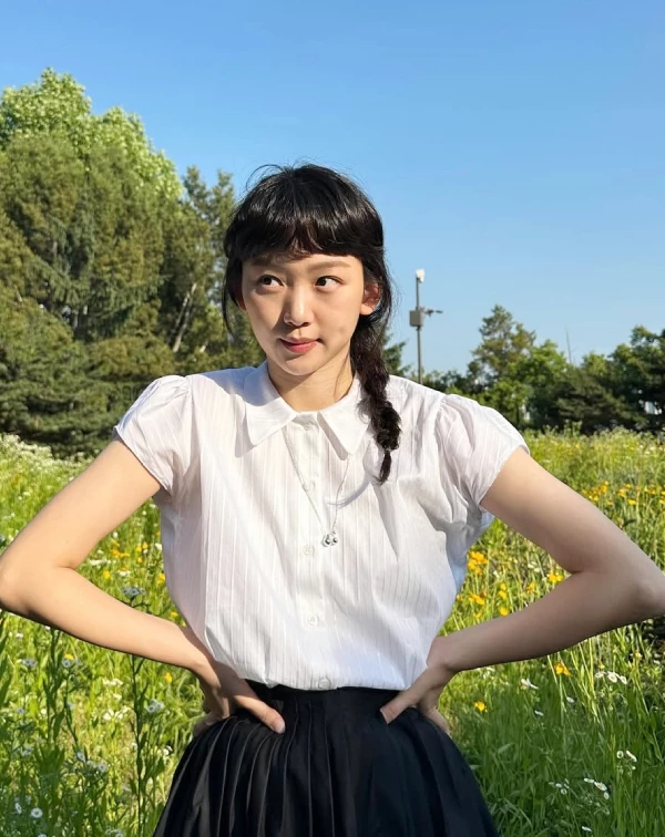 這種「黑、白配」雖然看著簡單，但短袖微澎的袖口設計與胸前的細緻銀鍊，都默默為秦基周注入了少女心，在陽光下閃閃發亮。當衣著顏色很基本時，就可以運用髮型和飾品來加分！像這樣穿上素色裙裝時，順手綁個隨性的側編辮子或丸子頭，再搭一條精緻的細項鍊，就能穿出夏日田園風的清爽與年輕感。