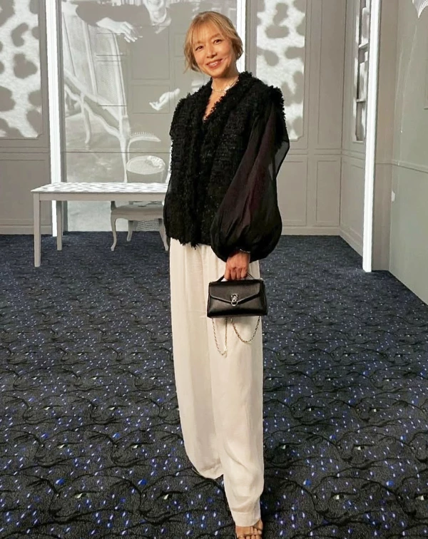 在Chanel的活動現場，山口智子再次展現極具個人風格的熟齡穿搭魅力。透過「厚重與輕透」的材質對比，巧妙化解全黑造型容易帶來的沉重感，也讓整體多了幾分俐落與少女感的靈動氣息。下身再以白色寬版西裝褲拉出黑白對比，也讓比例更顯修長、高級感十足的。而她利用微透紗材質修飾手臂線條的搭法，其實也很值得熟齡女性們參考，比起刻意全遮掩，「適度透膚」反而更能讓整體視覺看起來有精神，進而達到減齡效果。