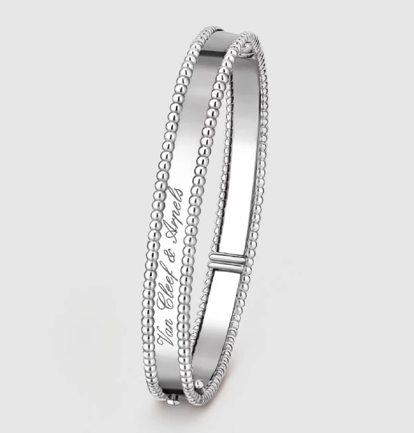 Van Cleef & Arpels（梵克雅寶）「Perlée® Signature」系列，以細膩圓珠飾邊勾勒輪廓，並以優雅的阿拉伯捲曲花紋字體鐫刻品牌標誌，展現經典識別與藝術美感的融合。經鏡面拋光處理後，18K白金表面映射出純淨而俐落的光澤，使整體更顯現代且精緻，低調之中蘊藏獨特辨識度。（商品價格約：NTD  268,000）