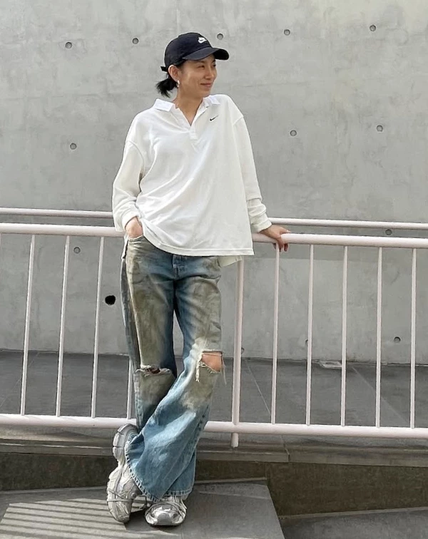 這套，金瑞亨展現了高超的街頭混搭功力，一件寬鬆的純白 Polo 衫上衣，搭配一條帶有強烈破壞感、甚至有些微髒污刷色的寬版牛仔褲，立刻就碰撞出奇妙的高街時尚感。如果你覺得破洞褲太誇張，可以換成普通的「寬版水洗藍牛仔褲」，重點是，腳上要踩一雙亮眼的銀色或彩色老爹鞋來點亮全身。