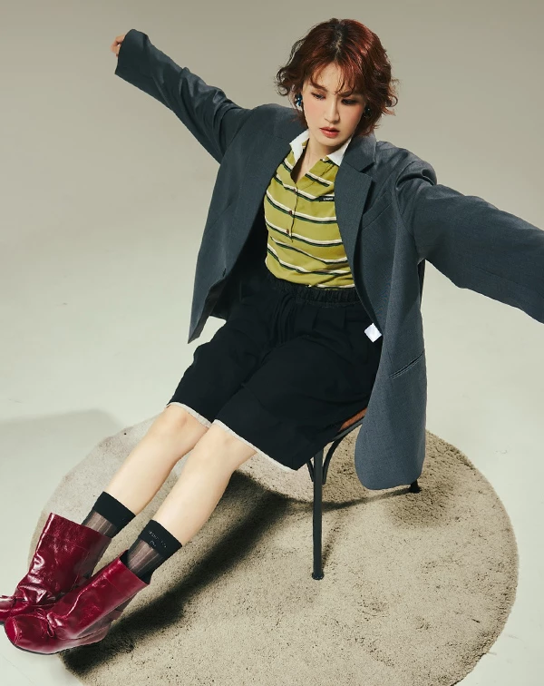 這套造型完美示範了曾沛慈如何利用「短裙」疊搭出高段位的「美式復古學院風」！她以百搭的黑色短裙為基調，內搭一件自帶復古感的芥末黃條紋Polo衫，並在外面罩上深灰色 Oversize 西裝外套，這種「大西裝 + 短裙」的組合，巧妙削弱了正裝的嚴肅感，反而穿出一種隨性又時髦的英氣。