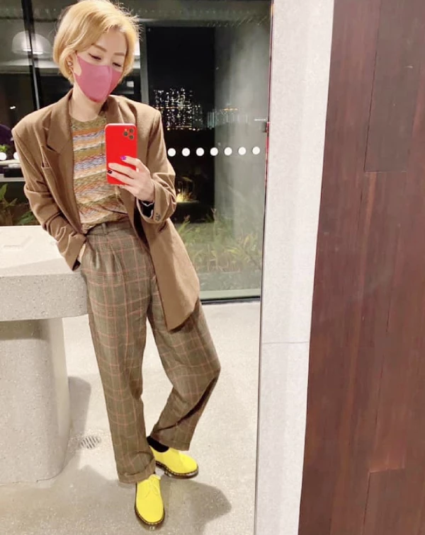 這套穿搭，我覺得完全展現了鄭秀文對復古玩味的高階減齡技巧。整體色調，以溫暖、低調的棕色系為基底，卻用一雙亮黃色短靴瞬間抓住視線，這種衝突感配色不僅讓造型更有活力，也巧妙地轉移了對年齡的關注，成功打造年輕又叛逆的感覺。復古元素的疊加，則是另一個亮點，格紋西裝套裝，配上條紋細節，將傳統復古單品玩出新意，不顯沉悶。