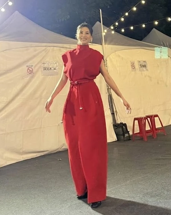 這套造型，完美示範了曾沛慈如何將「正紅色連身裙」穿出強大的女王氣場！她選用一件剪裁俐落的高領無袖長洋裝，極具建築感的廓形與大膽的紅，讓她在夜色中依然閃耀奪目。這套穿搭最神來一筆的細節，在於她巧妙利用同色系的細皮帶繫在腰間，並隨性垂下，這個舉動不僅抓出了明顯的腰身比例，更在簡約中增添了靈動感，成功打破長洋裝容易顯得厚重的沉悶感。