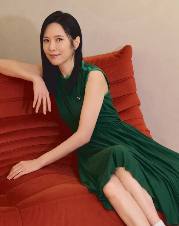 許多熟齡女性容易自限於黑白灰，天心這身復古飽和的「極致墨綠」洋裝直接給了我們新靈感。這類飽和色不僅具有極佳的顯白、提亮氣色效果，縮腰的傘擺剪裁更能自然勾勒出腰身。我們日常在穿這類優雅洋裝時，減齡的絕招就在腳上——千萬別配端莊的高跟鞋，那會顯得老氣沉重；像天心一樣混搭一雙復古的白色運動短襪與休閒鞋，利用這種微小的運動風反差，就能把及膝洋裝穿得像女大生一樣充滿活潑朝氣。