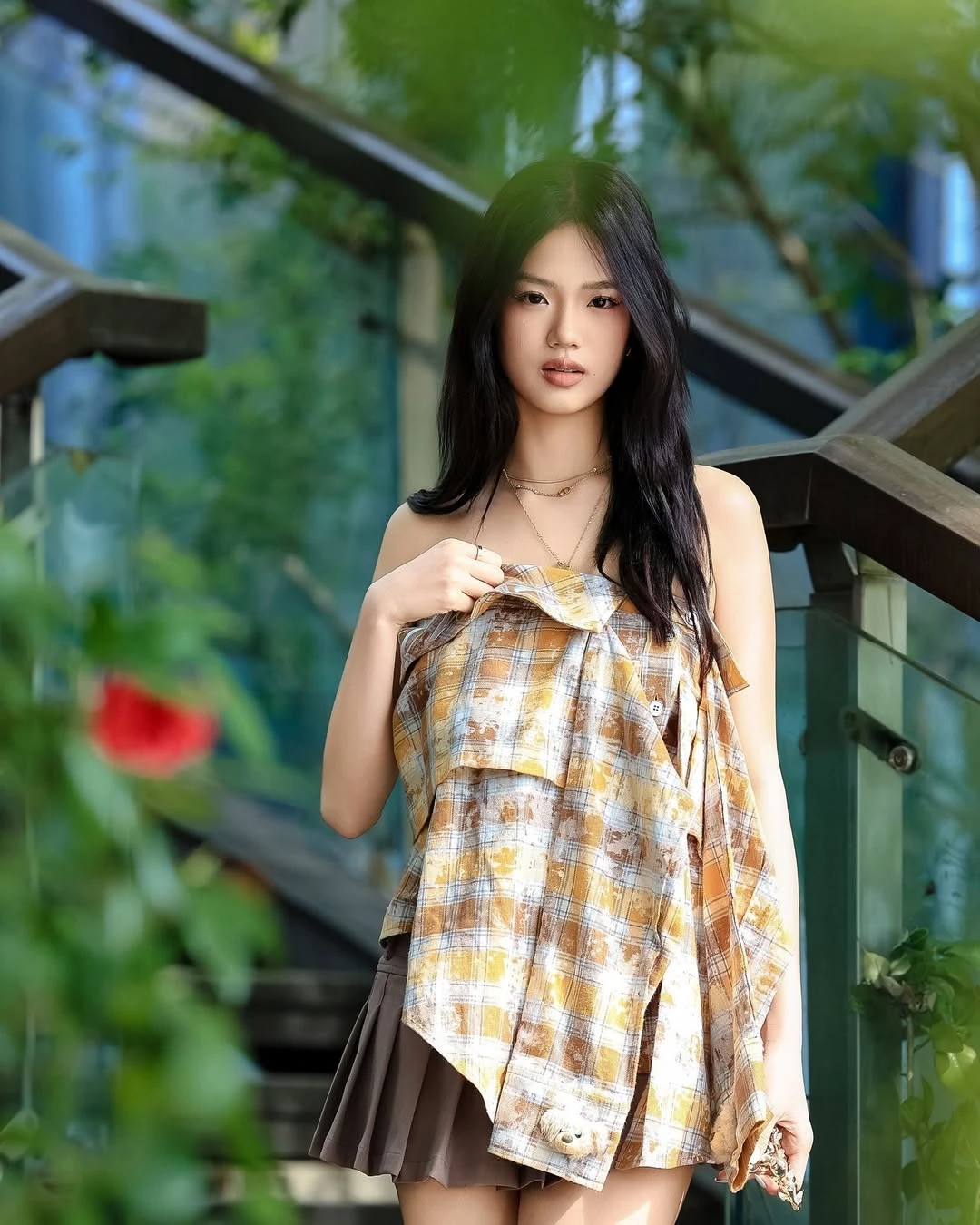 二女兒 Jaden 這套造型，把「層次」變成顯高關鍵。抹胸造在的色塊上衣，以不規則垂墜與拼接設計製造視覺落差，刻意模糊實際腰線位置，反而讓上半身比例顯得更短；下身搭配灰棕色百褶短裙，裙擺俐落展開，讓腿部線條自然成為視覺重心。整體色調維持在低彩度的大地色系，避免過於甜美或張揚，反而多了一點成熟的時髦感。這種上身有設計、下身夠簡潔的搭配方式，很適合想穿出比例優勢，又不想過度用力的日常造型，也讓顯高效果看起來毫不刻意。