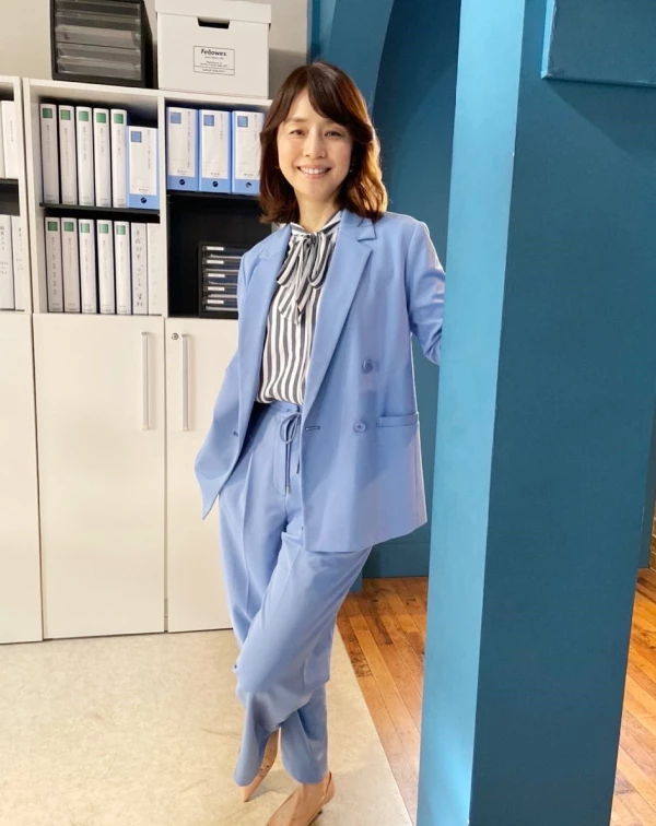 石田百合子選擇了自帶清爽感的亮藍色西裝套裝，視覺上瞬間提亮膚色，展現滿滿活力。內搭，則是大膽選用「黑白直條紋蝴蝶結襯衫」，直條紋帶來俐落的延伸感，而蓬鬆的蝴蝶結設計，則是巧妙地中和了西裝的硬朗，帶出一抹溫柔的女性化氣質。