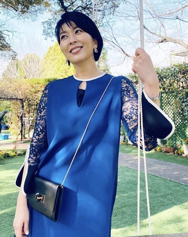 深藍色連身裙,在袖口處大面積拼接了細緻的藍色蕾絲花卉,並在領口做了小鏤空設計。微喇叭袖與白色滾邊的撞色細節,帶有濃濃的法式復古風情。穿著蕾絲時,熟齡女性最怕的就是顯得老氣或過於暴露,但我們不妨可以學學松隆子這樣,選擇具有與身上服裝的「同色系」蕾絲,讓肌膚隱約透出,既優雅又安全。最後再適度地搭配一款纖細的鏈帶小包,或閃耀的鑽石耳環、手鍊…等小珠寶點綴,貴氣又不顯老。
