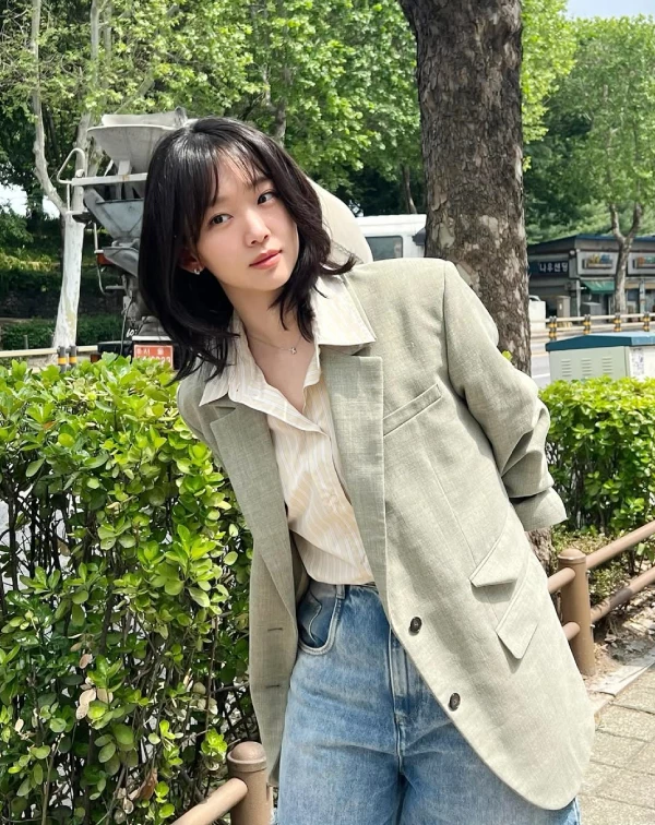 這張穿搭照，真的會讓人忍不住驚呼：這哪裡像奔四的人？基周歐尼挑選了一件帶有麻料質感的莫蘭迪綠西裝外套，內搭淺黃色細直條紋襯衫，不僅解開幾顆鈕扣製造V領的隨性，更聰明地將袖口隨意捲起。下半身搭配一件寬鬆的高腰淺色牛仔褲，微風吹亂的層次短髮，整個人散發出兼具知性與法式慵懶的逆齡高級感。