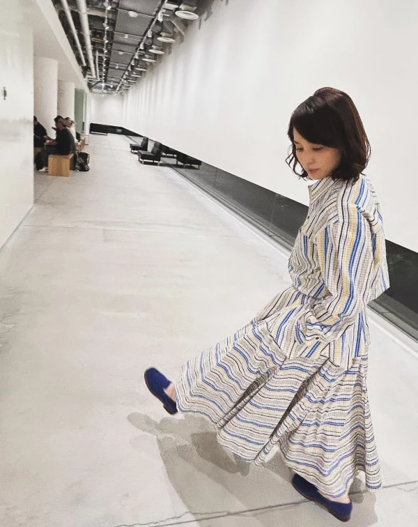 這套穿搭，完全捕捉到了石田百合子靈動又俏皮的一面！她穿上一襲滿版條紋的連身長裙，藍、黃、白交織的色調不僅充滿活力，整個人更散發出一種藝術家般的自由氣息。我們可以學她這樣穿，運用「條紋」展現永遠的青春元素，選擇剪裁具有層次感的長洋裝，並利用同色系配件來收斂視覺重點，就能像石田百合子一樣，在展現優雅品味的同時，依然保有少女般的清爽與朝氣！