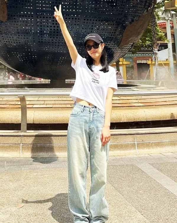 這套穿搭簡直是「美式復古少女」的完美範本,活力感都要溢出螢幕了!朴寶英聰明地用了小隻女必學的「上短、下長」黃金公式,短版白T輕微露出一截腰部肌膚,不僅顯得俏皮,更讓視覺腰線往上拉。下半身搭配刷色寬版牛仔褲,營造出一種「天生長腿」的鬆弛感。最後再戴上一頂黑色棒球帽和墨鏡,讓整個人看起來就像是剛從加州校園走出來的大學生,不僅減齡滿分,更把158公分的嬌小身材穿出了178公分的潮酷氣場,小隻女們對要直接複製貼上!