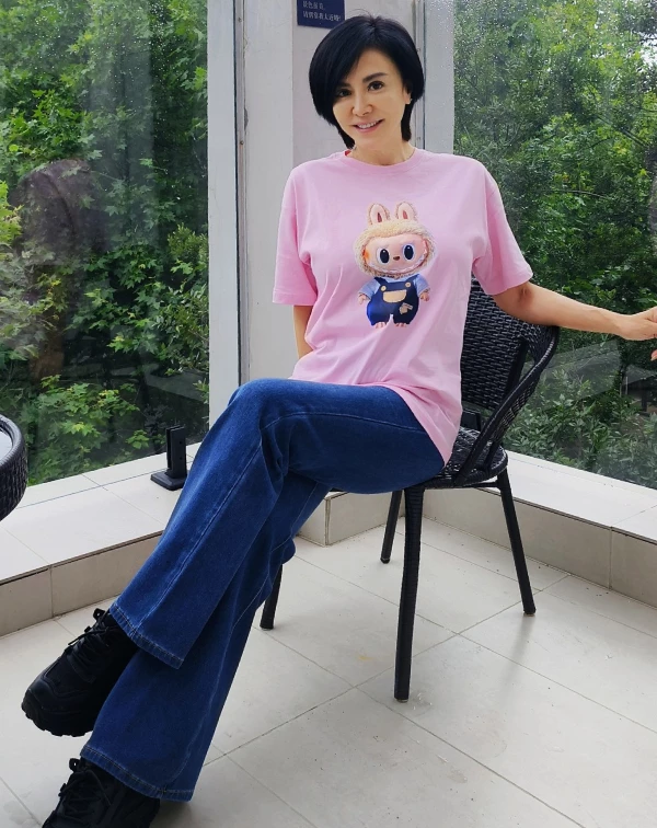 這張粉色穿搭照片最讓我驚豔的，莫過於田麗的「反差萌」！誰能想到昔日美豔動人的氣場女神，私下竟竟然也是紅遍全球的熱門玩偶Labubu小粉絲？！59歲的她穿上粉嫩色系的卡通T恤，非但沒有違和感，反而透出一種純真與俏皮。