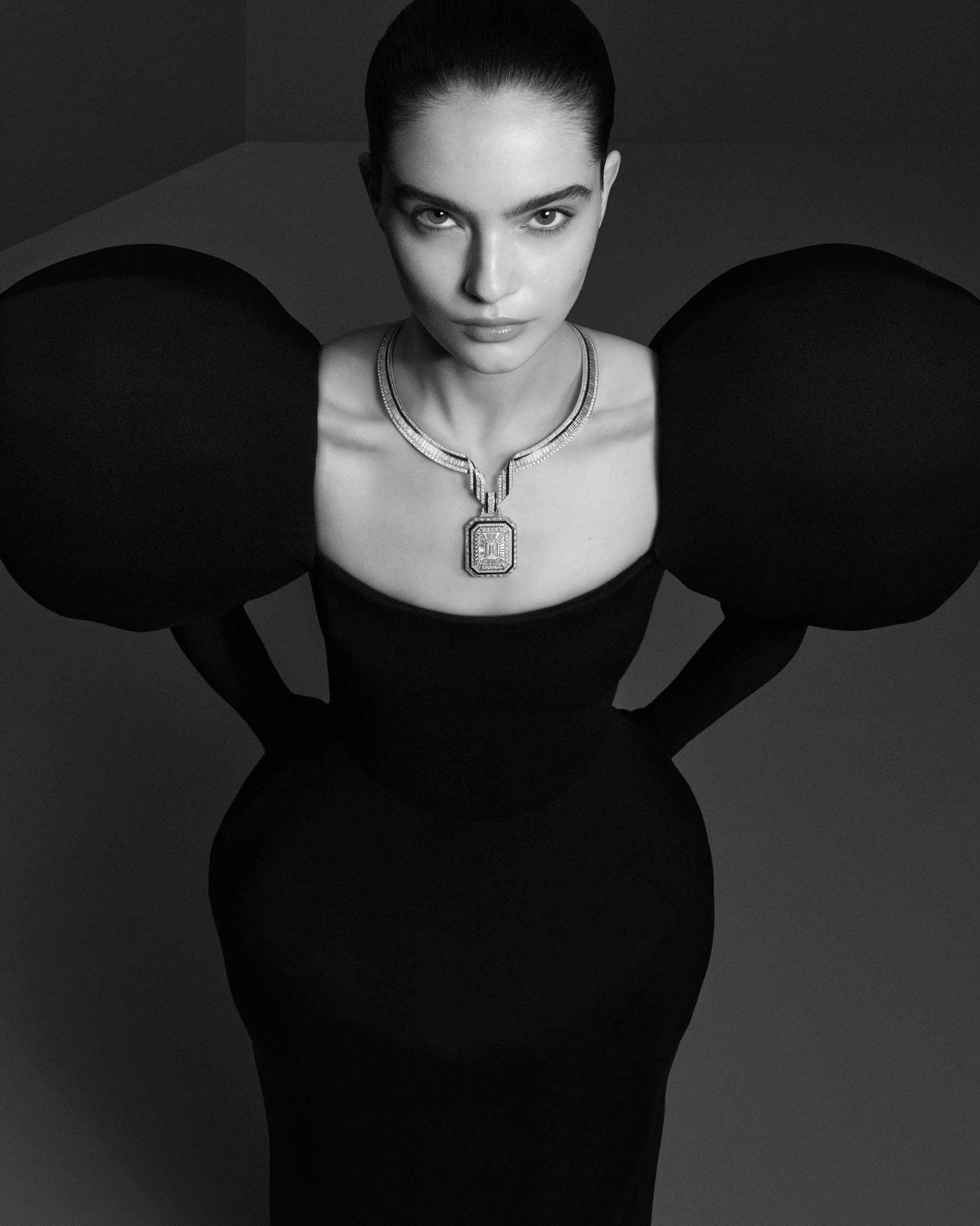 十九世紀末,巴黎和平街(rue de la Paix)匯聚了眾多珠寶與時裝品牌,這條繁忙街道一路延伸,通往當時仍顯靜謐的住宅廣場──Place Vendôme 芳登廣場。這裡是巴黎時髦仕女每日往返杜樂麗花園(Jardin des Tuileries)的必經之路。也因此,當多數商人仍選擇在人潮最密集的街區設點時,寶詩龍先生卻在這條動線與光線交會之處,看見了不同於眾人的可能。1893年,他率先進駐芳登廣場26號。此處一整日灑落的自然光,讓櫥窗中的珍貴寶石得以在無需修飾的狀態下,展現最真實的光彩。這個極具前瞻性的選擇,後來成為高級珠寶產業的關鍵轉折,眾多品牌相繼進駐,也讓芳登廣場逐步成為頂級奢侈的象徵。今年的首件作品〈The Address〉,正是對這個歷史性決定的當代回望。項鍊輪廓取自芳登廣場標誌性的八角形結構,白金與鑽石的單色純粹,對比深邃黑色漆面,彷彿將建築的理性秩序,轉化為一件可隨身體起伏的珠寶作品。它看似冷靜,卻擁有高度柔軟的佩戴結構,而這正是世家一貫的美學理念:在理性與感性之間,取得恰到好處的平衡。