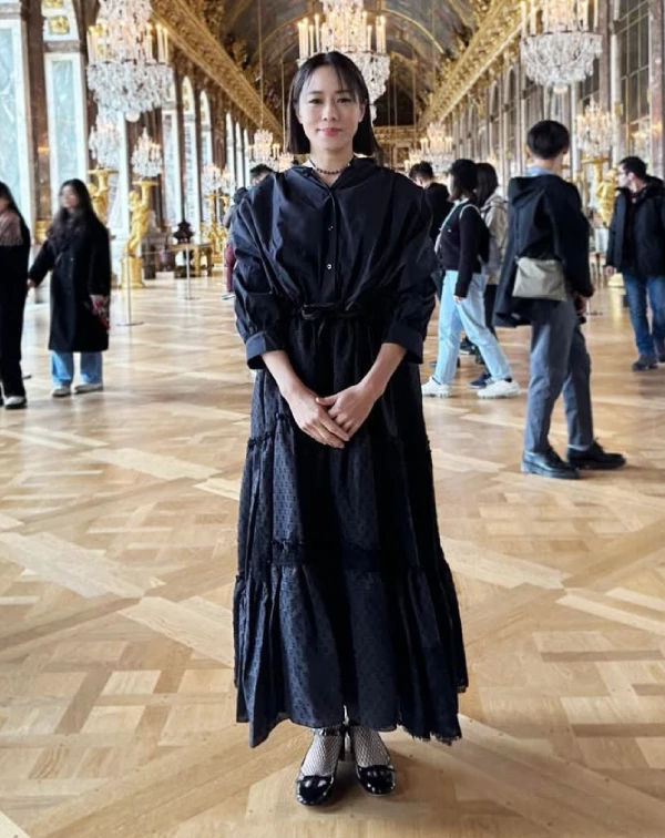林嘉欣身處華麗的巴黎宮殿,卻選了一身全黑洋裝。熟齡女性,穿全黑最怕顯得沉重或像去參加某種嚴肅場合,但她這件洋裝,在裙擺處帶有微透光的緹花與蕾絲細節,瞬間讓黑有了層次。想穿黑洋裝想減齡?關鍵就在於,打破大面積黑色的沉悶感。可以像林嘉欣一樣選擇上身略帶澎袖、下身有鏤空或網眼設計的款式,微微透出肌膚感。最後,再用帶點少女心與個性的配件,就能把黑洋裝穿得優雅又神祕。