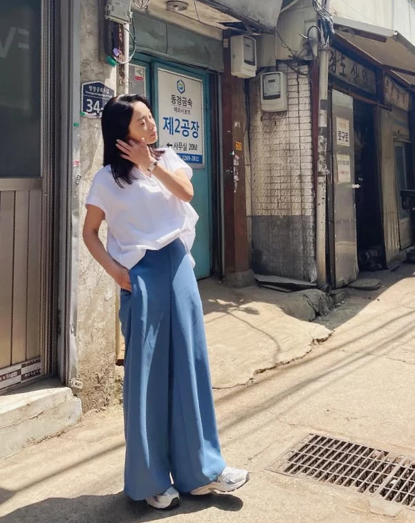 如果說白色是減齡聖品，那這張照片裡的徐令姬，簡直是代名詞！這種明亮的藍、白色系搭配，瞬間讓她的氣色看起來既清爽又時髦得毫不費力。我們這個年紀的女性，夏天一定要學會用「亮點色」來提亮自己。別再只敢穿全身黑或卡其色了！試著像她一樣，用「白上衣+藍色褲」打造清爽逆齡感。既能有吸睛的視覺效果，又不會顯得過於突兀，絕對是我們顯年輕、顯好氣色的秘密武器。