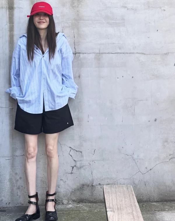 這套造型,完美演繹了「夏天如何利用高彩度配件,點亮穿搭」,高賢廷以淺藍色條紋襯衫,搭配黑色短褲,清爽色調瞬間降溫。不過最精彩的減齡穿搭重點,莫過於那頂亮眼的紅色棒球帽,與腳下的繫帶瑪莉珍鞋。紅色帽子,不僅能增添年輕活力,更為簡約襯衫注入街頭感;而復古瑪莉珍鞋與短褲的組合,則巧妙地拉長腿部比例,散發出如大學生般的俏皮感。