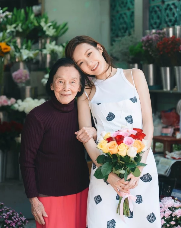 很多同齡女性擔心單穿細肩帶洋裝會露手臂或顯得太過性感，李佳芯給了我們一個教科書級的解答：「雙層疊穿」。第一步，先穿上一件極簡的純白削肩無袖背心，接著疊穿上帶有黑色幾何玫瑰印花的細肩帶白洋裝。這個技巧，巧妙地遮蔽了可能讓人自在的副乳或過多裸露感，卻保留了細肩帶的清爽與浪漫。整體色調保持乾淨的黑與白，不僅襯托出極佳的氣色，走在街頭更是滿滿的鄰家姐姐好感度。