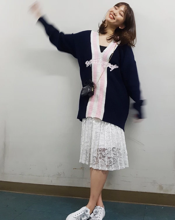 這套穿搭，則是展現了基周歐尼甜美的一面。她穿著深藍色V領開襟衫，開襟處有可愛的粉色條紋和字母設計。下半身，則是搭配白色蕾絲長裙及厚底白鞋。這種混搭，既有開襟衫的復古甜美，又有蕾絲裙的仙氣，最後用運動鞋收尾，讓整體造型不會過於嬌柔造作。