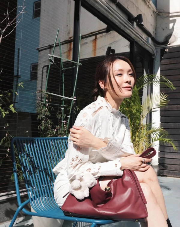 在照片中，李佳芯完美示範了什麼叫「不費力的初夏逆齡感」！很多同齡女性擔心蕾絲會穿得像桌布，那是因為版型沒選對。首先，挑選一件帶有精緻幾何鏤空剪裁的白色蕾絲襯衫洋裝，領口帶點小立領設計，能順便修飾頸部線條；第二步，將頭髮溫柔地低紮成雙辮或低馬尾，這樣能瞬間打破蕾絲的貴氣，多一分鄰家氣息，讓整個人散發出有如在午後巴黎街頭喝咖啡的鬆弛感。