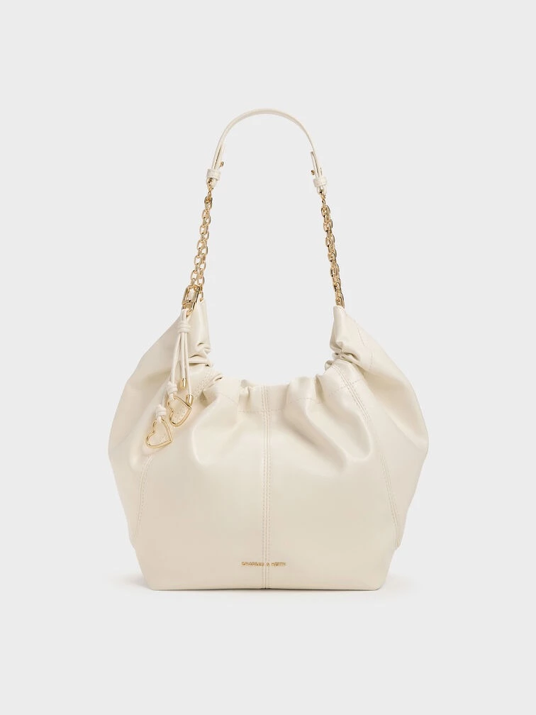 Charles & Keith Ciara 流浪包奶油色,紋路PU皮革搭配柔軟抓皺輪廓,鏈條背帶結合金屬吊飾,磁釦開合精緻優雅。
