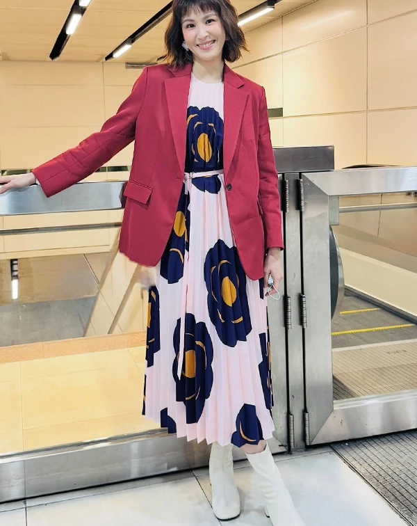曾沛慈特別選用粉色基底搭配深藍色大花朵的百褶長裙，大膽的對比圖騰視覺張力十足，透過百褶細節帶出流動的藝術感，讓整個人散發出知性又大方的氣息。其整套最厲害的配色巧思，在於上半身，挑選了一件與裙子花朵色系呼應的暗紅色西裝外套，挺拔的剪裁正好壓住了印花裙容易產生的膨脹感，讓整體造型顯得俐落有神。