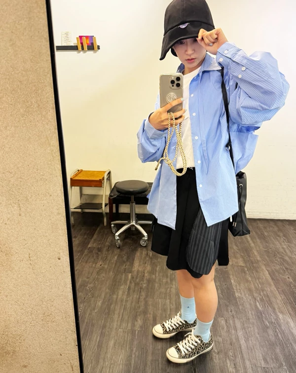 誰說年過35、40歲以上，就只能走成熟路線呢？眼前這套造型，便是完美示範曾沛慈如何穿出「大學生感」的率性與可愛。她以寬鬆的藍白條紋襯衫，作為外罩，內搭簡潔白T，營造出不費力的清爽層次；下身，則選用黑色拼接短裙，並大膽踩上豹紋帆布鞋與水藍色短襪，利用對比色點亮視覺，讓整體散發滿滿的校園青春活力。