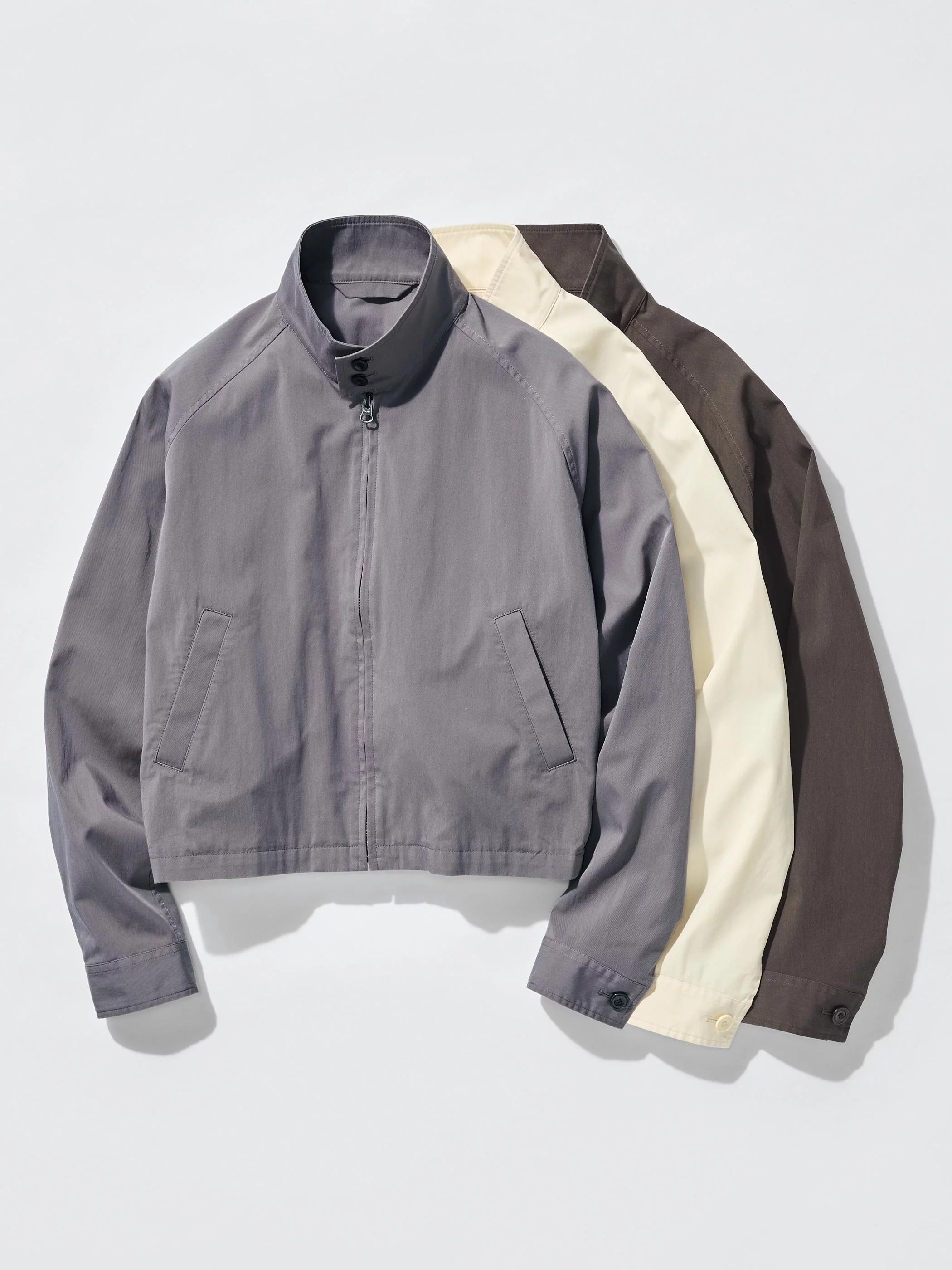 短版布勞森外套向來是 Uniqlo U 的代表性輪廓之一，本季版本以棉質尼龍斜紋材質打造，保留挺度與輕盈感之間的平衡。整體採無內裡設計，使外套在春夏氣候下依然保持舒適透氣。短版箱型剪裁搭配俐落肩線，穿起來既有結構感，也不會顯得過於正式。細節設計同樣延續巴黎設計團隊一貫的克制美學，金屬拉鍊開合為整體增加俐落質感，領口的雙鈕釦則帶出略帶工裝味的立體輪廓。背面加入鬆緊設計，讓外套在行走與活動時呈現自然弧度。深棕色、灰藕紫與象牙白三種配色，都屬於低飽和色系，非常容易融入日常衣櫃。搭配高腰褲或寬版牛仔褲，都能輕鬆建立簡潔有力的春季造型。